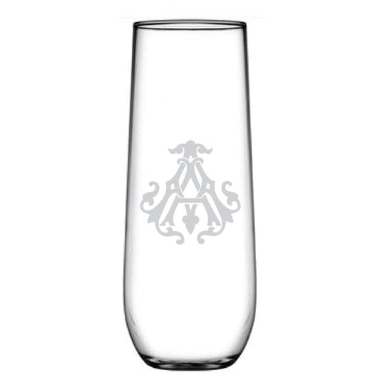 A tall 1-Letter Monogrammed Stemless Champagne Flute features a clear glass with a centrally etched symmetrical emblem and an intricately engraved initial, exuding elegance.