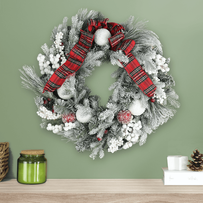 red and white tartan wreath on green wall above fireplace mantel