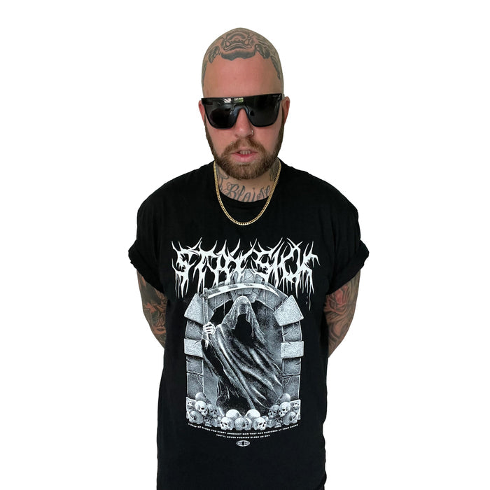 A bald, tattooed man with a beard and dark sunglasses wears a Stay Sick Clothing black T-shirt with a gothic Reaper skull design and a gold chain, standing against a plain white background.