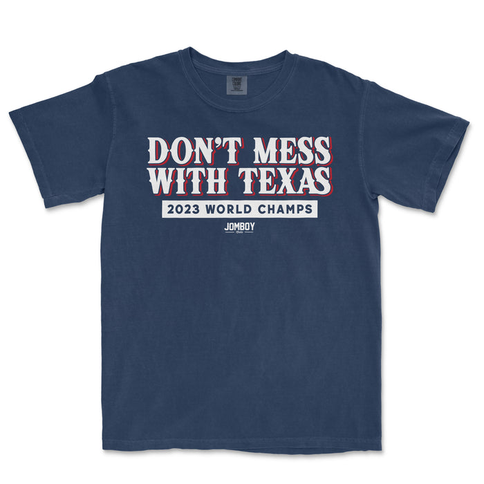 Comfort Colors T-shirt featuring "Don’t Mess With The Champs" slogan, "2023 World Champs," and Jomboy logo in white and red on navy fabric.
