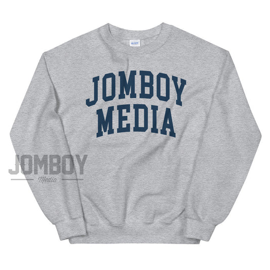Gray sweatshirt with "JOMBOY MEDIA" printed in bold navy blue letters across the front.