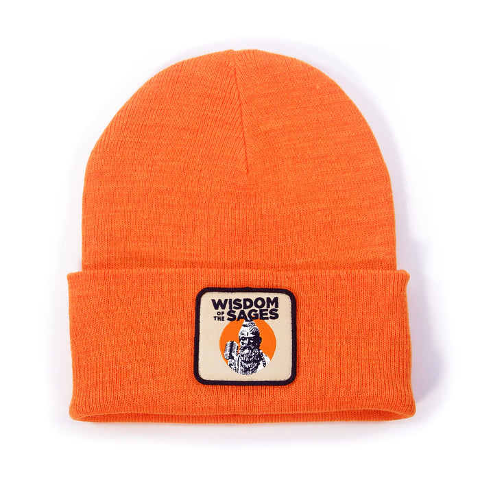 An orange knit beanie by Wisdom of the Sages with a folded brim, rectangular patch with an illustrated figure and “WISDOM of the SAGES” in black—crafted from sustainable Polylana material.