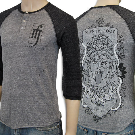 A heather grey and black Mantralogy raglan shirt featuring a “Mantralogy” logo on the front left chest and a large goddess face with skulls and ornate patterns plus MANTRALOGY above the graphic on the back.