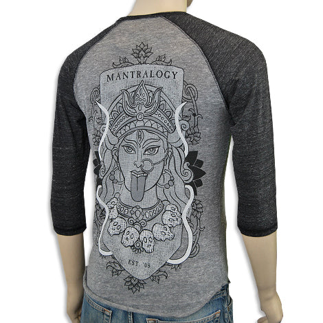 A mannequin wears a gray and black raglan shirt from Mantralogy, featuring bold lines and detailed patterns depicting a Hindu goddess graphic on the back with "MANTRALOGY" above the design.