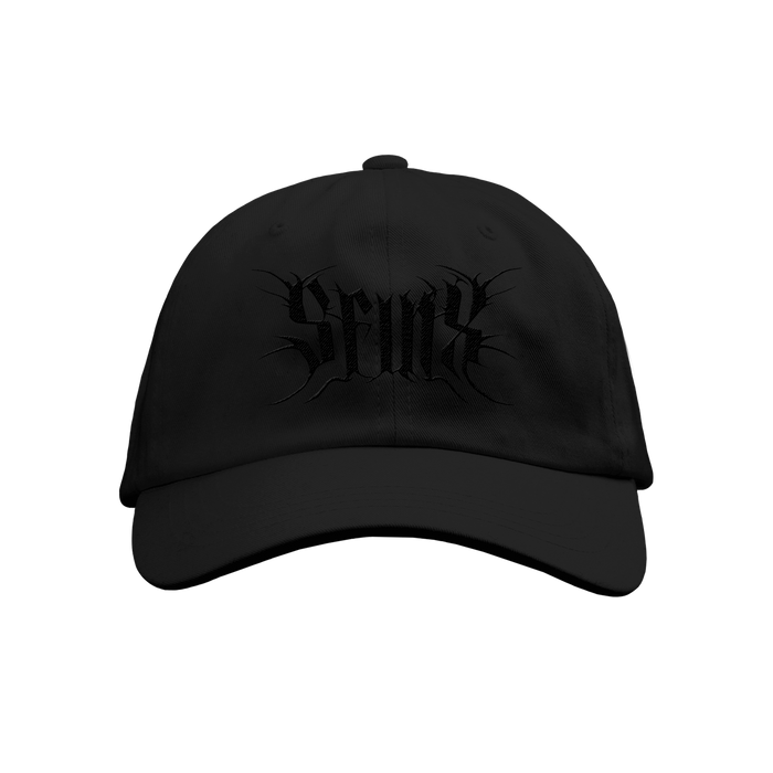 The SFINX black baseball cap features Seaux embroidered in a stylized gothic font on the front. Its solid black design stands out. Available for presale; shipping date provided at checkout.