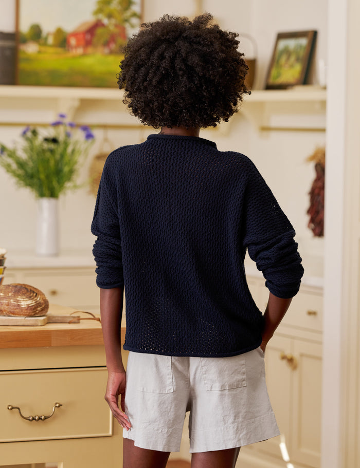 Person wearing a navy sweater and light shorts in a home setting