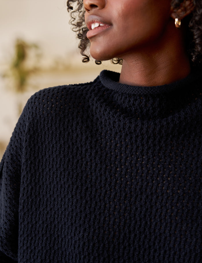 Person wearing a dark blue knitted sweater with a blurred background