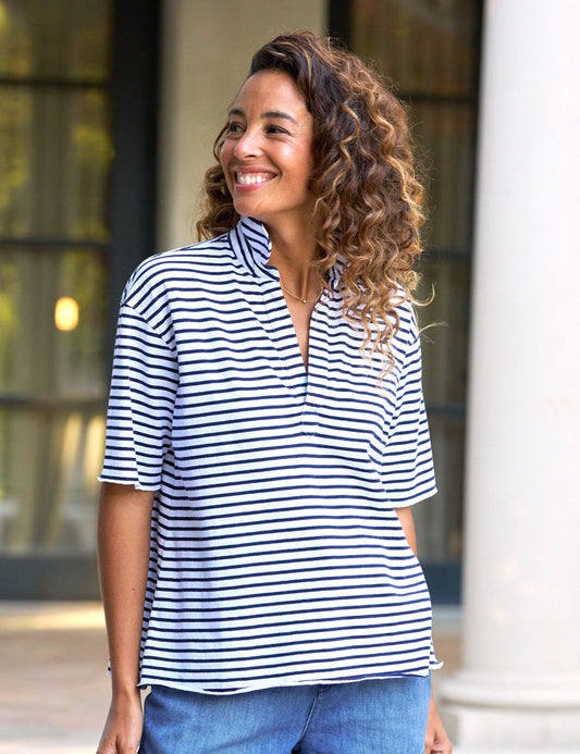 A woman wearing a navy and white striped short-sleeved henley top with a preppy v-neck.