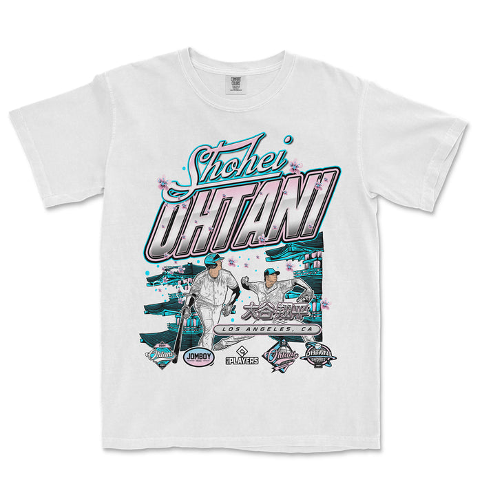 White T-shirt featuring pastel-colored graphics of Shohei Ohtani, Japanese characters, and Los Angeles landmarks with cherry blossom accents.