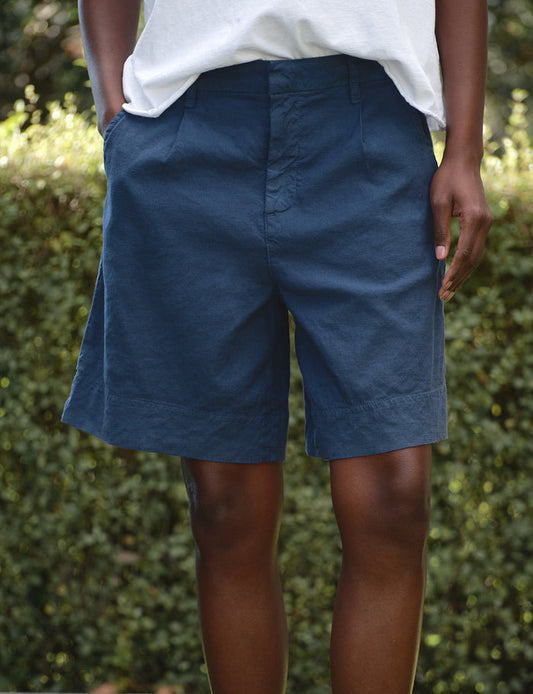 Person wearing blue shorts standing on grass with a blurred green background