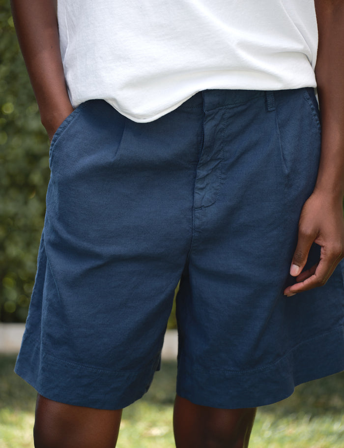 Person wearing blue shorts and a white shirt with a blurred green background